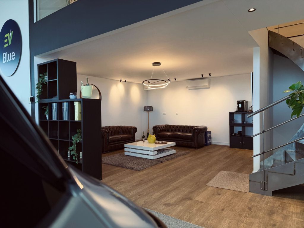 Intérieur du showroom EV Blue avec voitures électriques en exposition et logo visible